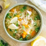 Lemon Chicken Orzo Soup in a green bowl with lemon slices.