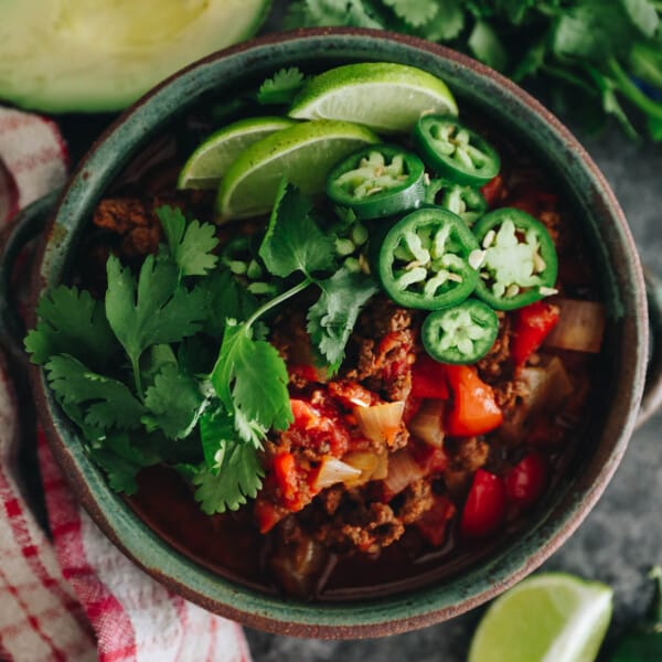carnivore chili recipe with no beans in a green bowl and topped with jalapeno, lime and cilantro.