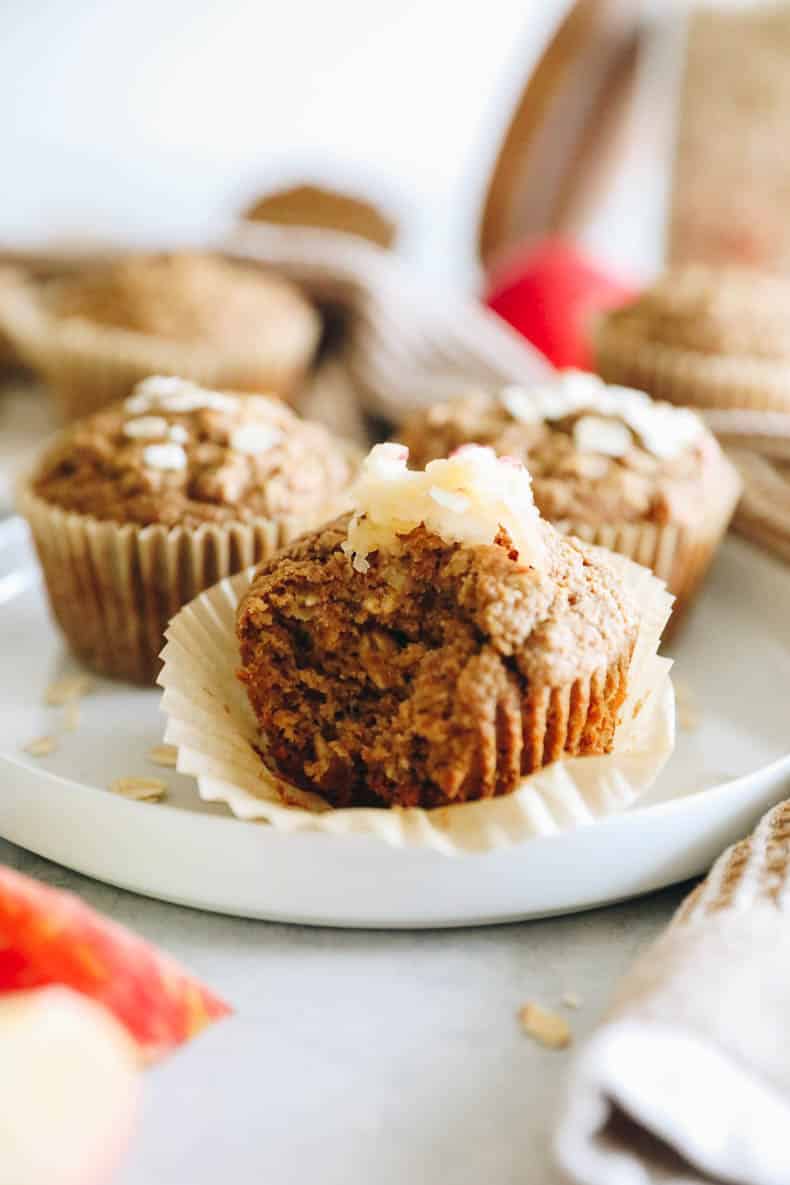 apple muffin on a white plate with a bite taken out of it.