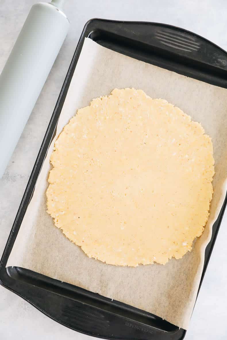 rolled out almond flour pie crust on a parchment lined sheet pan