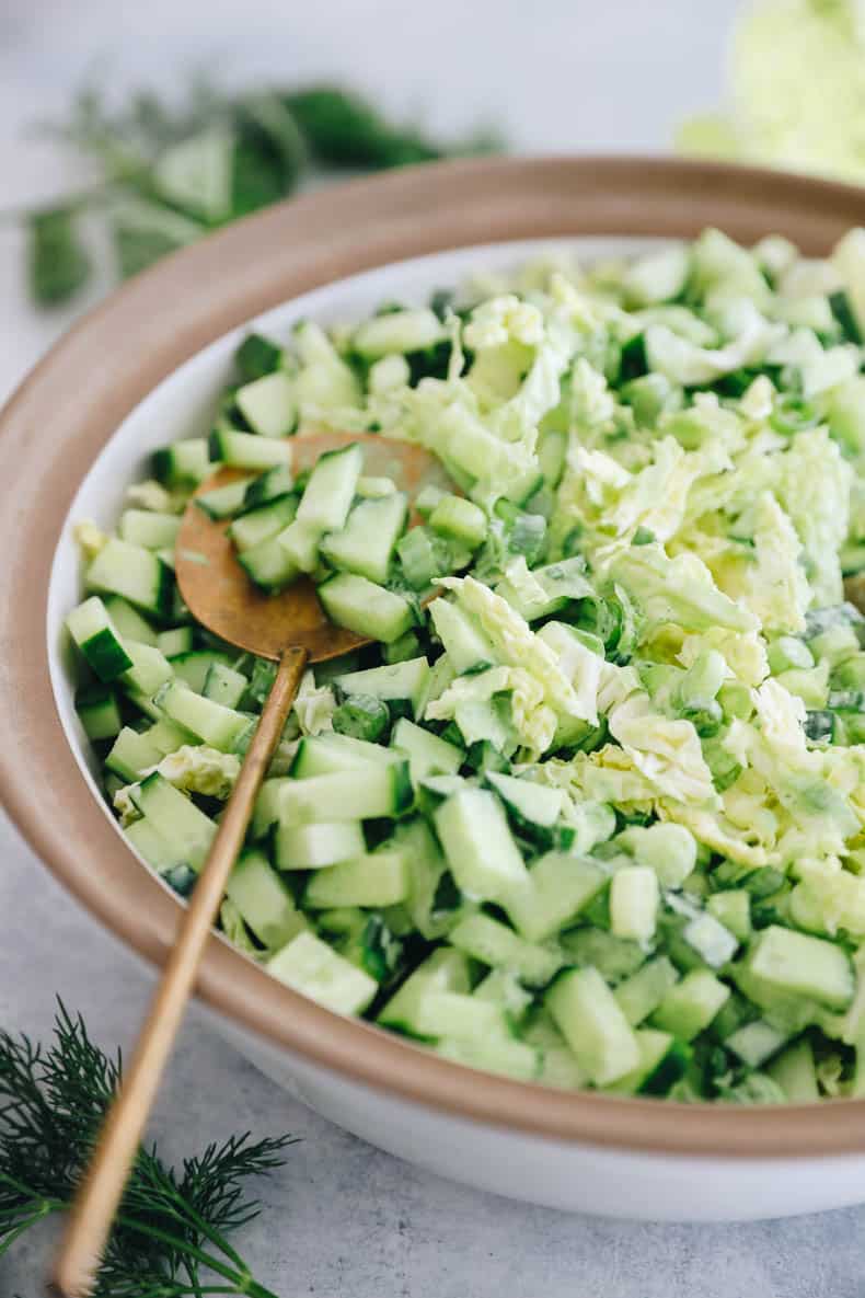 up close image of cabbage, cucumber, green onion goddess salad topped with a green goddess dressing