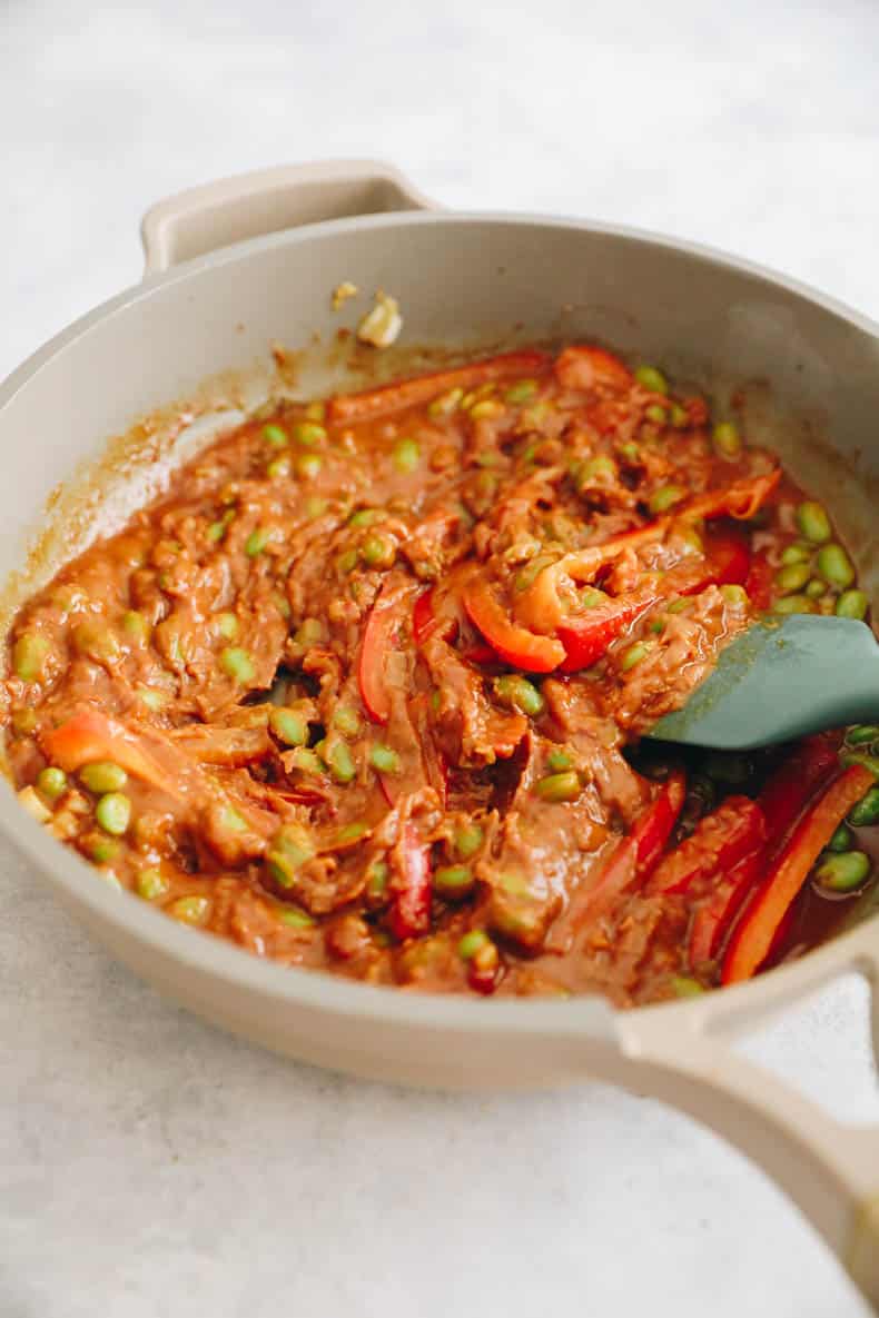peanut sauce in a pan with sliced bell pepper and edamame