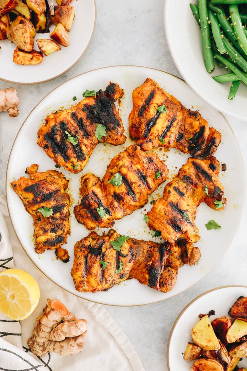 Grilled turmeric chicken on a white plate.