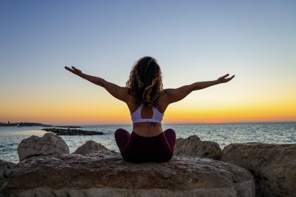 woman sitting on the stone in front of the ocean