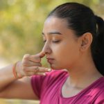 A young woman practicing alternate nostril breathing outdoors