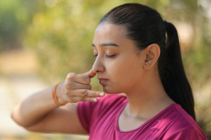 A young woman practicing alternate nostril breathing outdoors